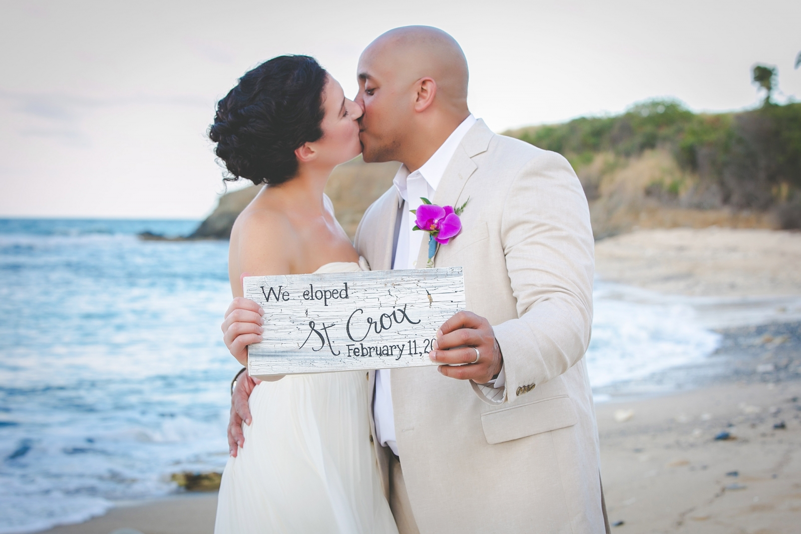 St. Croix wedding couple kissing on beach holding a wedding sign