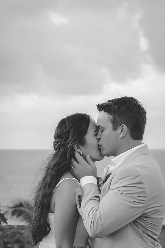 St. Croix groom kissing bride's cheek with ocean in the background