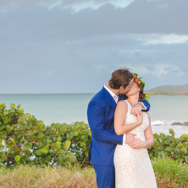 St. Croix bride and groom kissing on hillside overlooking the ocean