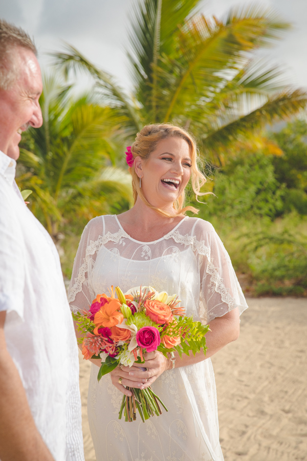 St. Croix bride laughing on beach with bouquet bouquet