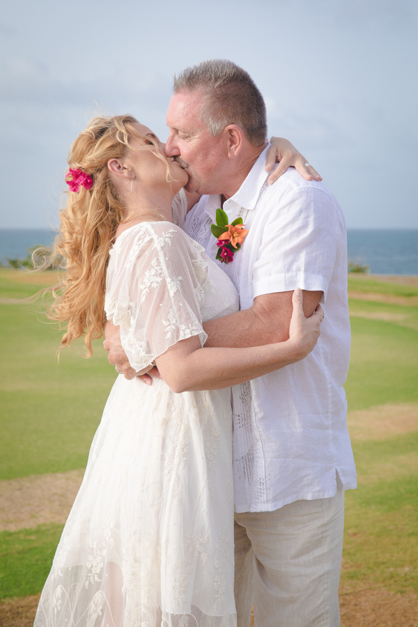 St. Croix bride and groom kissing on hillside overlooking the ocean