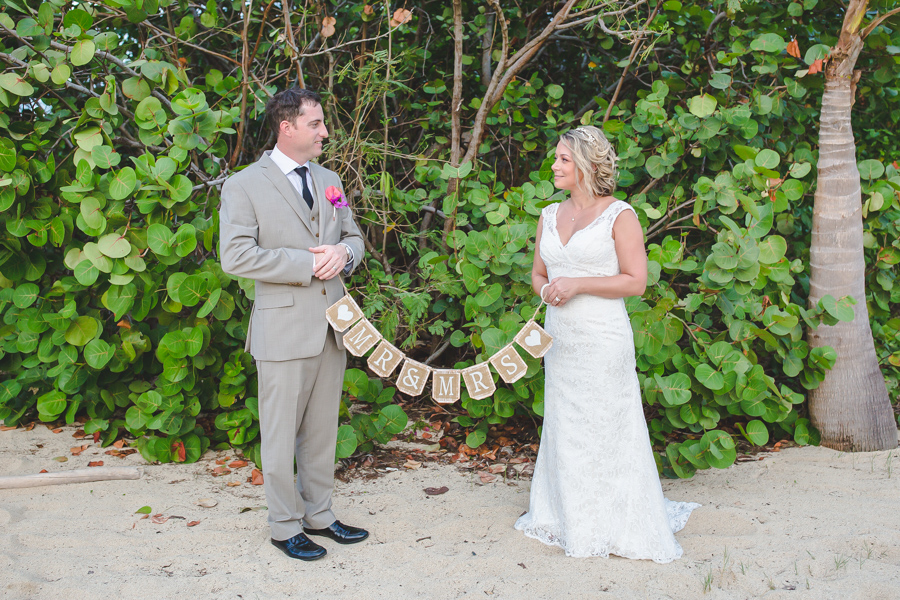 St. Croix bride and groom holding wedding sign on the beach