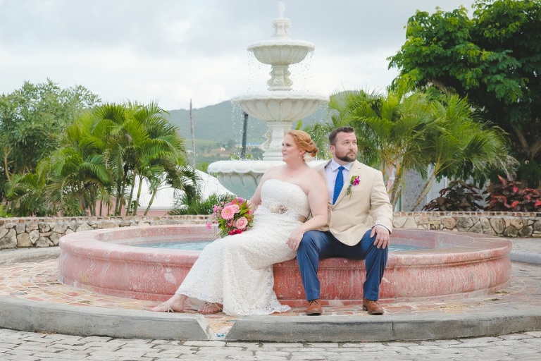 St. Croix bride and groom sitting on water fountain edge